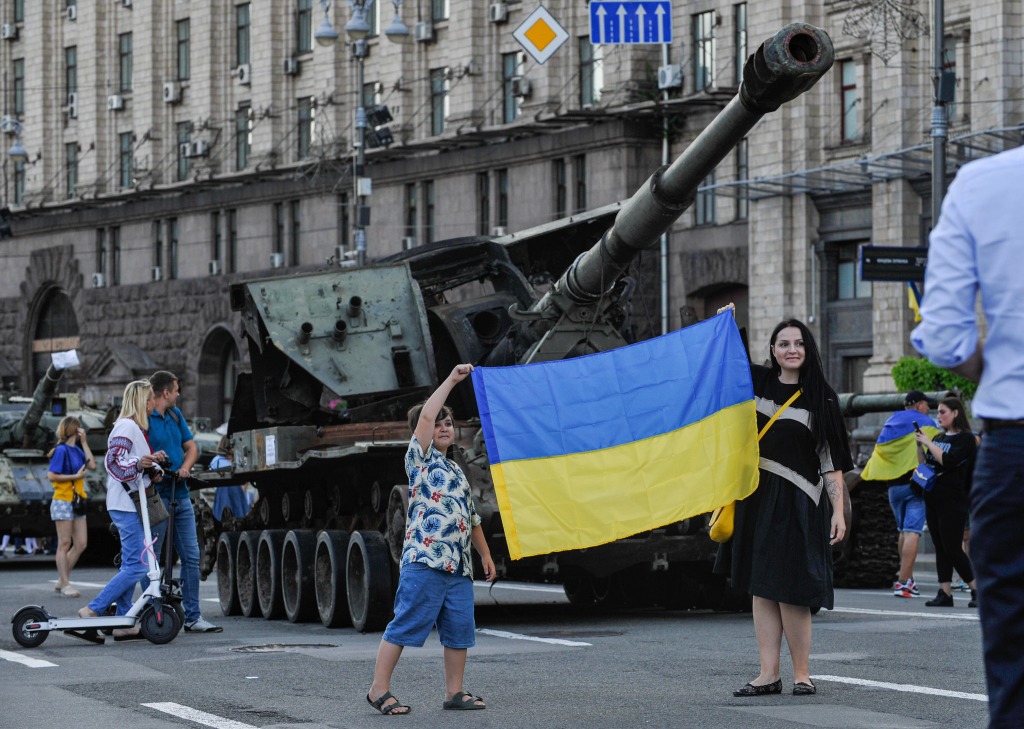 People take pictures with the Ukrainian flag near destroyed Russian army equipment displayed at Khreshchatyk in Kyiv, Ukraine on Aug. 23, 2022.