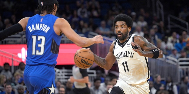 Brooklyn Nets guard Kyrie Irving (11) drives in front of Orlando Magic guard R.J. Hampton (13) during the first half of an NBA basketball game Tuesday, March 15, 2022, in Orlando, Fla. 