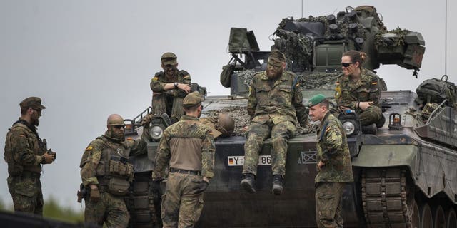 German Bundeswehr soldiers of the NATO enhanced forward presence battalion wait to greet German Chancellor Olaf Scholz ahead of his arrival at the Training Range in Pabrade, some 60km (38 miles) north of the capital Vilnius, Lithuania, Tuesday, June 7, 2022. 