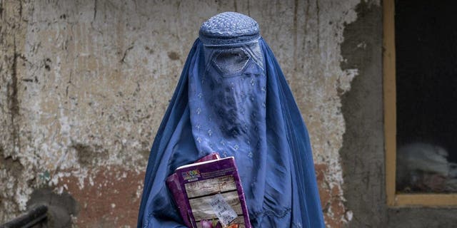 An Afghan woman leaves an underground school, in Kabul, Afghanistan, Saturday, July 30, 2022. She attends this underground school with her daughter who is not allowed to go to public school. 