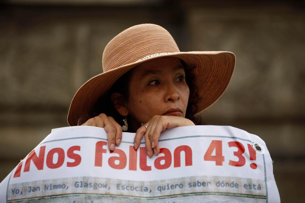 A woman carries a banner that reads in Spanish "We are missing 43," referring to the 43 missing students during a march in Mexico City, on November 26, 2015. 