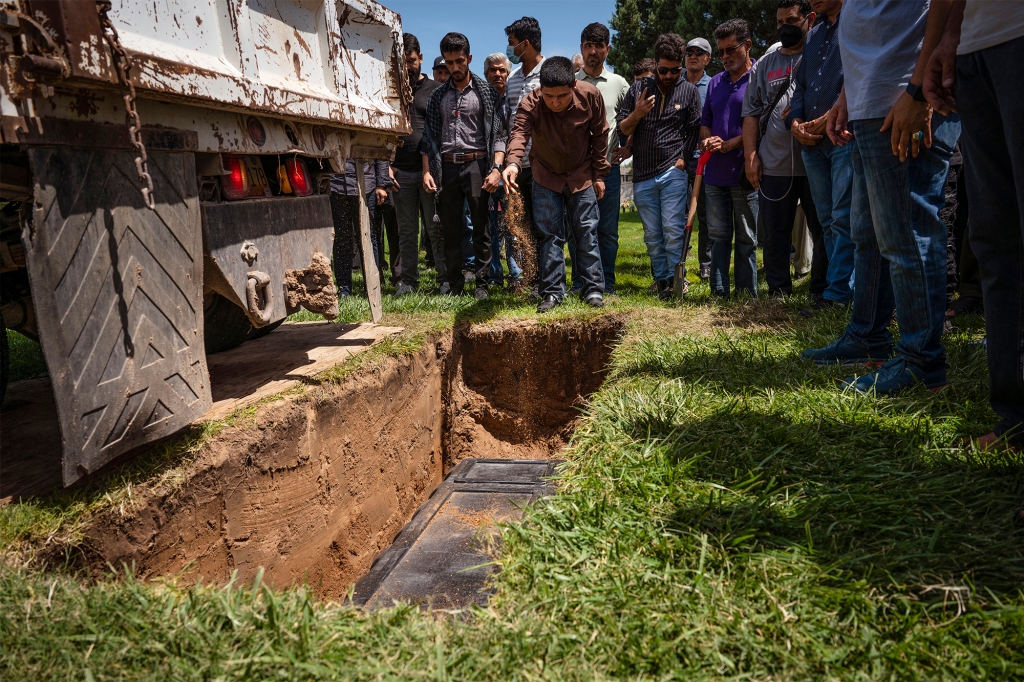 Altaf Hussain sprinkles dirt over the grave of his brother Aftab Hussein at Fairview Memorial Park in Albuquerque, N.M., on Friday, Aug. 5, 2022.