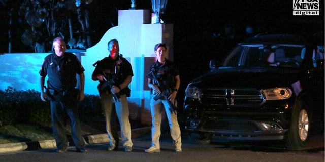 Three men with guns are seen standing outside the gates of Donald Trump's private Florida estate after the FBI raided the sprawling property allegedly looking for classified documents.