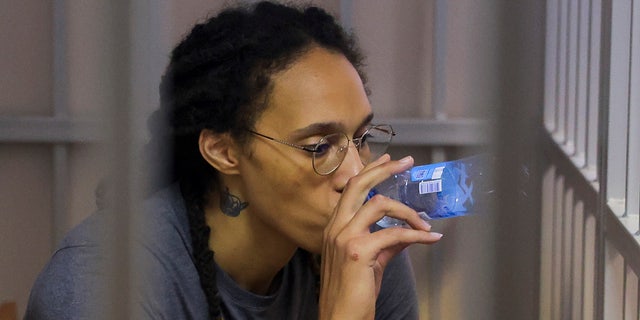 WNBA star and two-time Olympic gold medalist Brittney Griner drinks water as she listens to the verdict in a cage in a courtroom in Khimki just outside Moscow, Russia, Thursday, Aug. 4, 2022.