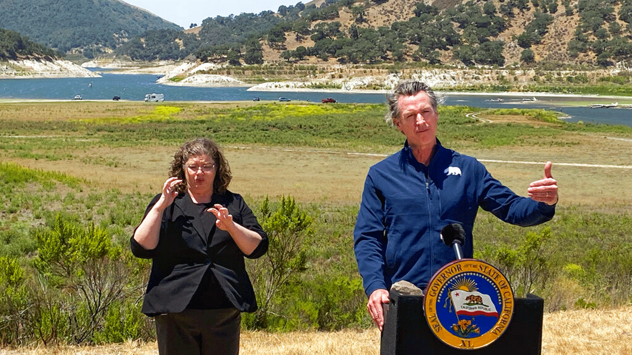 Gov. Gavin Newsom stands at the edge of a diminished Lopez Lake near Arroyo Grande, California.