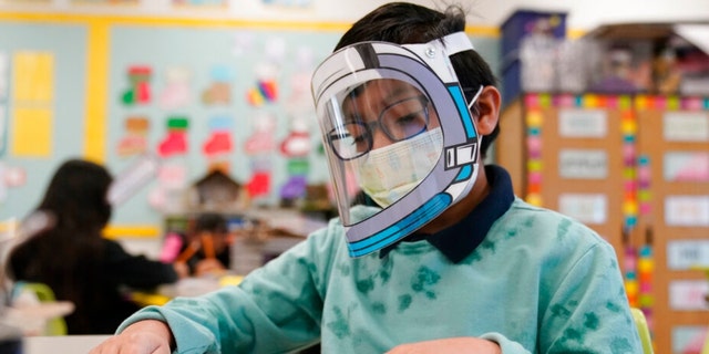 A student wears a mask and face shield in a fourth grade class during the COVID-19 pandemic at Washington Elementary School Jan. 12, 2022, in Lynwood, Calif. 