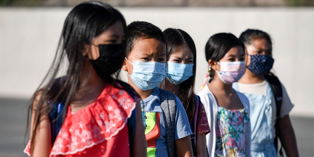 Masked students wait to be taken to their classrooms at Enrique S. Camarena Elementary School July 21, 2021, in Chula Vista, Calif. 