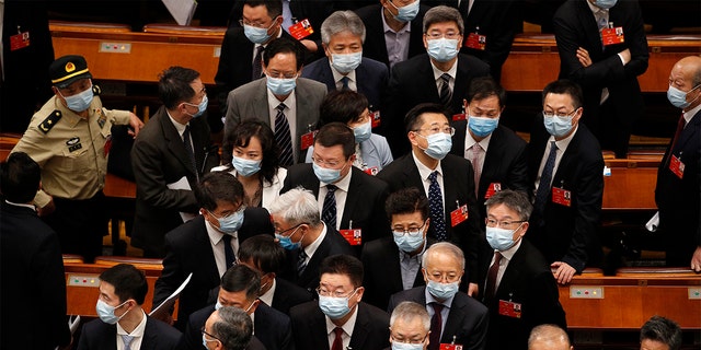 Delegates wearing face masks to protect against the spread of the new coronavirus leave after the opening session of the Chinese People's Political Consultative Conference at the Great Hall of the People in Beijing, Thursday, May 21, 2020. 