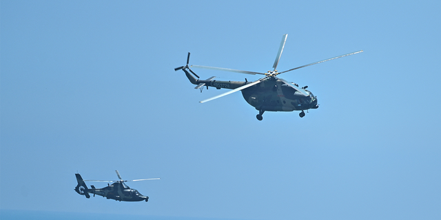 Chinese military helicopters fly past Pingtan island, one of mainland China's closest point from Taiwan, in Fujian province on August 4, 2022, ahead of massive military drills off Taiwan following US House Speaker Nancy Pelosi's visit to the self-ruled island. - China is due on August 4 to kick off its largest-ever military exercises encircling Taiwan, in a show of force straddling vital international shipping lanes following a visit to the self-ruled island by US House Speaker Nancy Pelosi. (Photo by Hector RETAMAL / AFP) (Photo by HECTOR RETAMAL/AFP via Getty Images)