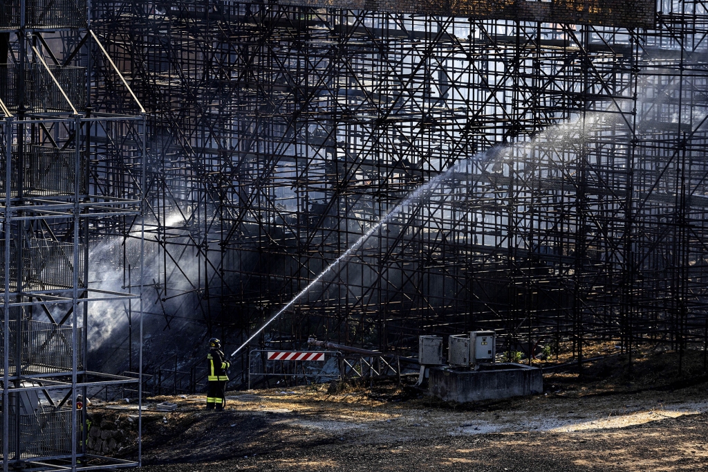 Firefighters hose down a structure to extinguish a fire at the Cinecitta studios southeast of Rome, on August 1, 2022.