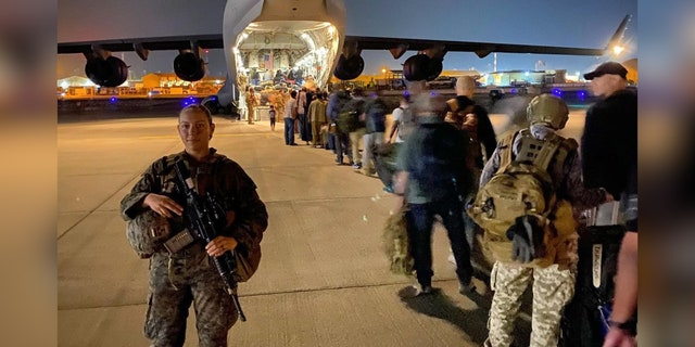 Gee escorts evacuees onto a plane at Hamid Karzai International Airport on Aug. 22, 2021.