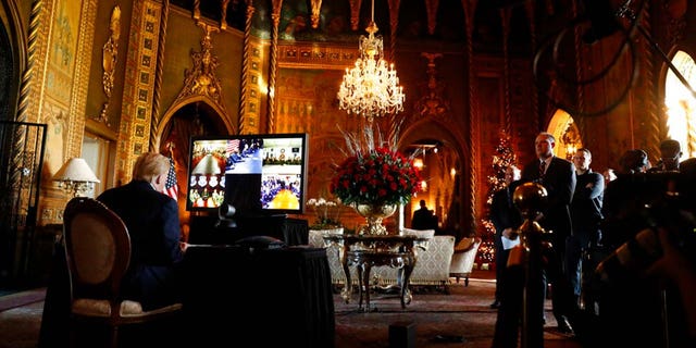 FILE: Then-President Donald Trump listens during a Christmas Eve video teleconference with members of the military at his Mar-a-Lago estate in Palm Beach, Fla., Dec. 24, 2019.