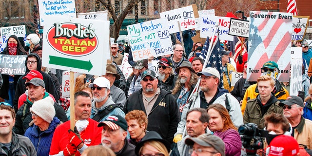 People hold signs  during a protest against the coronavirus shutdown in front of State Capitol in Madison, Wisconsin, on April 24, 2020.