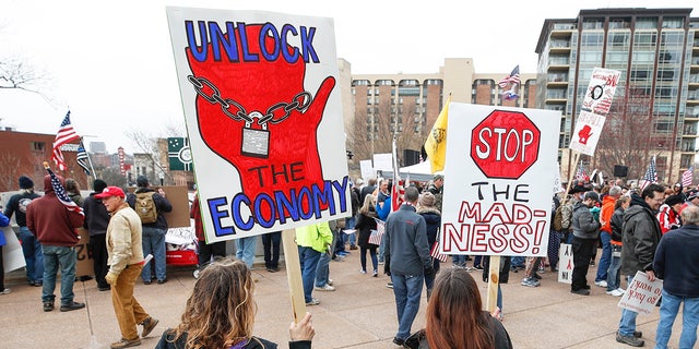 People hold signs during a protest against the coronavirus shutdown in front of the State Capitol in Madison, Wisconsin, on April 24, 2020.