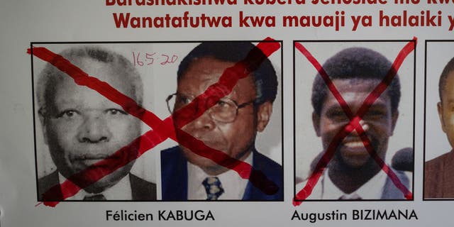 A red cross is seen drawn on the face of Augustin Bizimana (R), one of the most-wanted fugitives from the 1994 Rwandan genocide, next to the red-crossed face of Felicien Kabuga (L), who was arrested last week in Paris, on a wanted poster at the Genocide Fugitive Tracking Unit office in Kigali, Rwanda, on May 22, 2020.