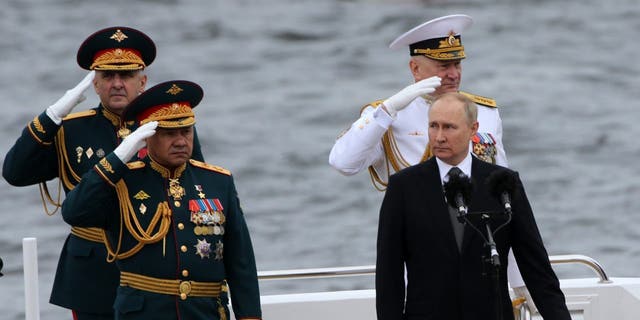 Russian President Vladimir Putin (2R), Defense Minister Sergei Shoigu (L) and Chief Commander of the Russia Fleet Nikolai Yevmenov (R) seen aboard of the boat during the Navy Day Parade, on July, 31 2022, in Saint Petersburg, Russia. 