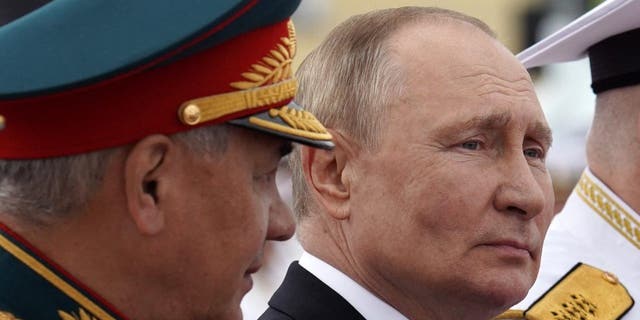 Russia's President Vladimir Putin sits next to Russia's Defence Minister Sergei Shoigu (L) as he takes part in the main naval parade marking the Russian Navy Day, in St. Petersburg on July 31, 2022. 