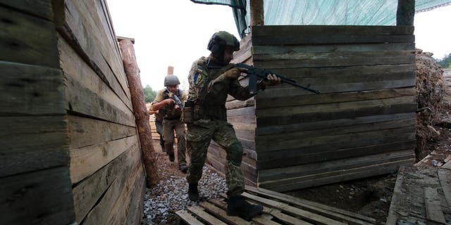 Armed National Guard servicemen walk along a trench at one of the sections of a defence line outside Kharkiv, Kharkiv Region, northeastern Ukraine. 