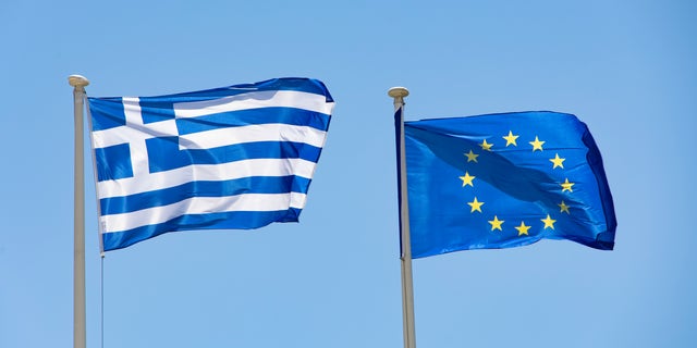 Flags of Greece and Europe on a flagpole waving in the wind. The flag of Europe on a flagpole waving in the blue sky during a summer sunny day at the Greek capital city Athens. The flag of Europe or the European Flag is the symbol of the Council of Europe CoE and The European Union EU. The national flag of Greece, Flag of the Hellenic Republic or Greek flag with the White and Blue colors symbolise the Greek sky and sea named as Galanolefki meaning The Blue and White. The Greek flag as seen on a flagpole waving in the blue sky during a summer sunny day at the Greek capital city Athens. July 2022 (Photo by Nicolas Economou/NurPhoto via Getty Images)