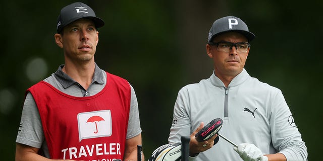 Rickie Fowler talks with his caddie Joe Skovron during a practice round prior to the Travelers Championship at TPC River Highlands on June 22, 2022, in Cromwell, Connecticut. 