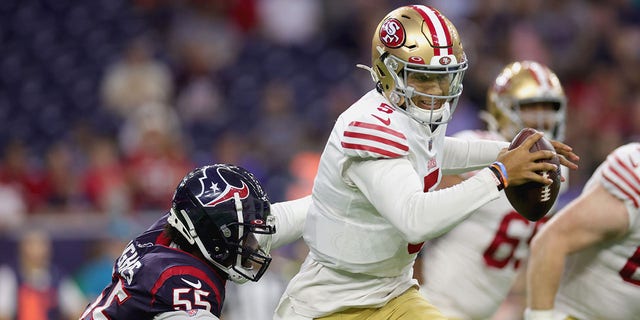 Trey Lance of the San Francisco 49ers scrambles away from Jerry Hughes of the Houston Texans during the first quarter of an NFL preseason game at NRG Stadium in Houston, Texas, on Thursday.