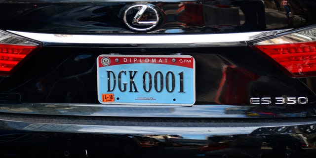 A Lexus automobile with a diplomatic license plate is parked along a street in New York, New York. 