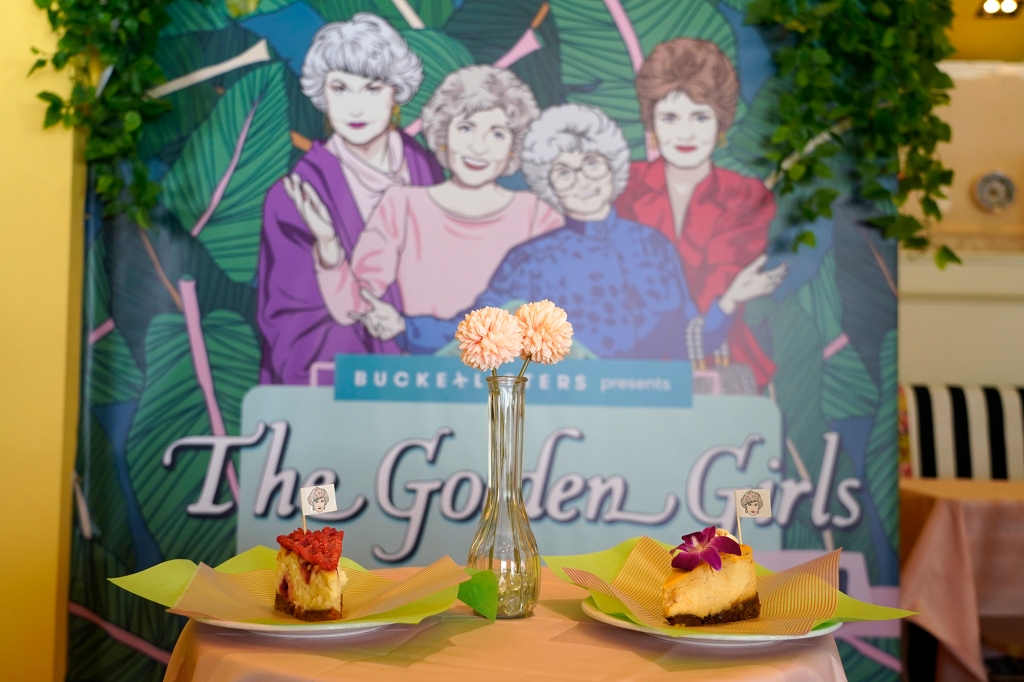 Cheesecake dessert items are pictured in front of a portrait of "The Golden Girls" cast at the new Golden Girls Kitchen pop-up restaurant in LA.