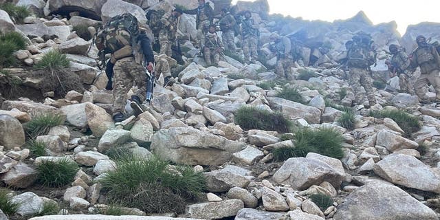 National Resistance Front fighters scale a mountain.