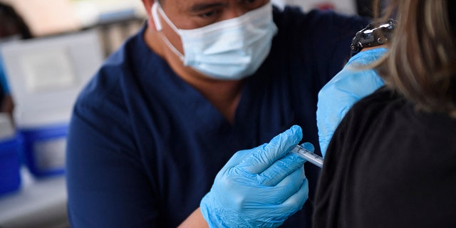 A nurse administers a dose of the Pfizer COVID-19 vaccine to a high school student during a City of Long Beach Public Health COVID-19 mobile vaccination clinic at the California State University Long Beach campus Aug. 11, 2021, in Long Beach, Calif. 