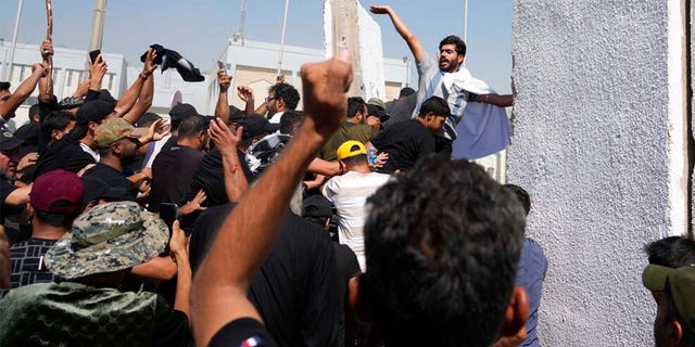 Supporters of Shiite cleric Muqtada al-Sadr try to remove concrete barriers in the Green Zone area of Baghdad, Iraq, Monday, Aug. 29, 2022. 