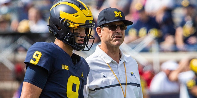 Michigan quarterback J.J. McCarthy, #9, stands with head coach Jim Harbaugh during warmups before an NCAA college football game against Western Michigan in Ann Arbor, Michigan, Saturday, Sept. 4, 2021. 