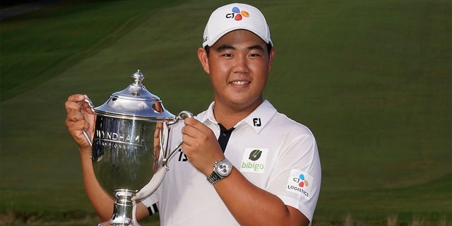 Joohyoung Kim, right, of South Korea, poses with the trophy after winning the Wyndham Championship golf tournament in Greensboro, N.C., Sunday, Aug. 7, 2022. 