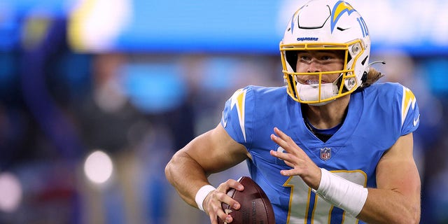 Justin Herbert of the Los Angeles Chargers runs as he looks up field during a game against the Kansas City Chiefs at SoFi Stadium in Inglewood, California, on Dec. 16, 2021.