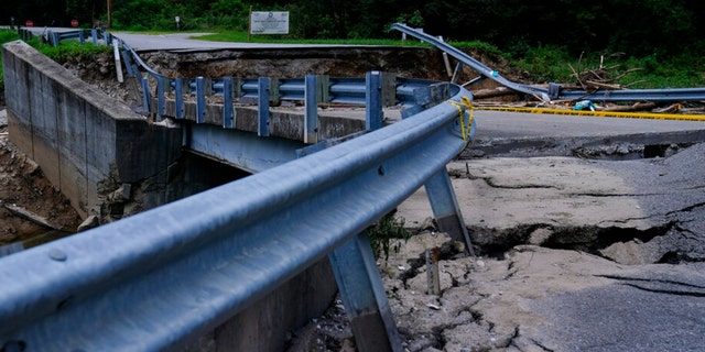 The road leading to a bridge above a creek cracks and breaks after massive flooding on Thursday, Aug. 4, 2022, in Chavies, Kentucky.