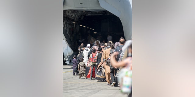 Families board an Air Force C-17 Globemaster III during an evacuation at Hamid Karzai International Airport in Kabul, Afghanistan, on Aug. 24, 2021.