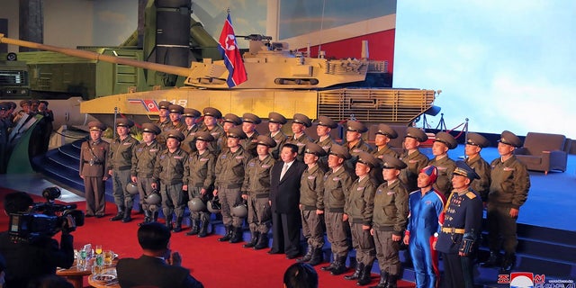 North Korean leader Kim Jong Un, center, poses for a group photo with fighter pilots who made the demonstration flight at the opening of an exhibition of weapons systems in Pyongyang, North Korea, on Monday. (Korean Central News Agency/Korea News Service via AP)