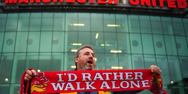 A man sells scarves outside the Old Trafford ground, Manchester, England, Monday Aug. 22, 2022, ahead of an organized protest against the Manchester United owners before the Premier League match between Manchester United and Liverpool.