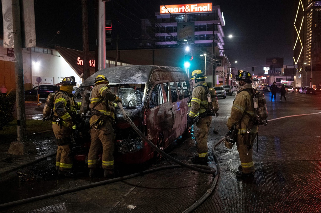 Firefighters work at the scene of a burnt transport vehicle after it was set on fire by unidentified individuals in Tijuana Mexico, on Aug. 12, 2022.