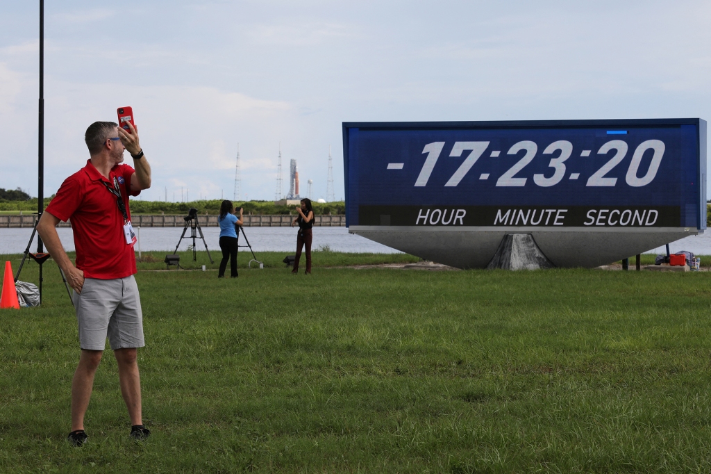 Journalists take pictures near the countdown clock as NASA's next-generation moon rocket, the Space Launch System (SLS) rocket with its Orion crew capsule perched on top, stands on launch pad 39B in preparation for the unmanned Artemis 1 mission at Cape Canaveral, Florida, U.S. August 28, 2022.