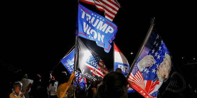 Supporters of former U.S. President Donald Trump wave flags as they gather outside his Mar-a-Lago home after Trump said that FBI agents raided it, in Palm Beach, Florida, U.S., August 8, 2022. 