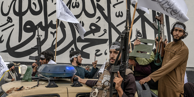 Taliban fighters hold their weapons as they celebrate one year since they seized the Afghan capital, Kabul, in front of the U.S. Embassy in Kabul, Afghanistan, on Monday, Aug. 15.