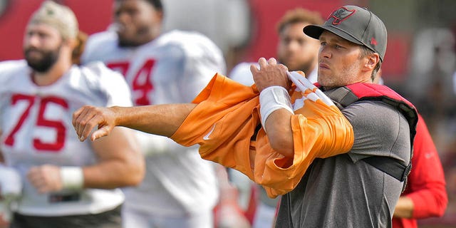 Tampa Bay Buccaneers quarterback Tom Brady puts on his jersey during practice with the Miami Dolphins on Aug. 10, 2022, in Tampa, Florida.