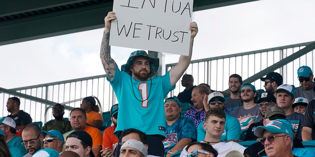 A Dolphins fan holds a sign in support of quarterback Tua Tagovailoa during drills at the team's practice facility, Saturday, July 30, 2022, in Miami Gardens, Florida.