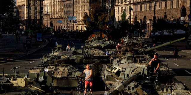 People walk around destroyed Russian military vehicles installed in downtown Kyiv, Ukraine, Wednesday, Aug. 24, 2022.