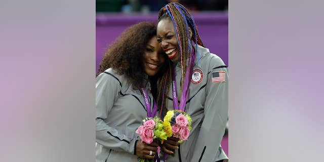 Serena Williams, left, and Venus Williams of the United States celebrate on podium after receiving their gold medals in women's doubles in London.