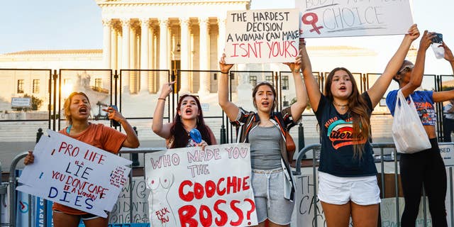 Pro-choice protesters hold signs in front of the Supreme Court building.