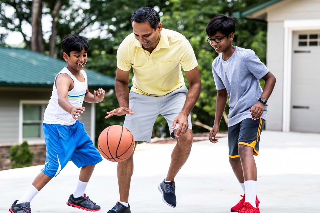 Father and sons playing basketball in driveway