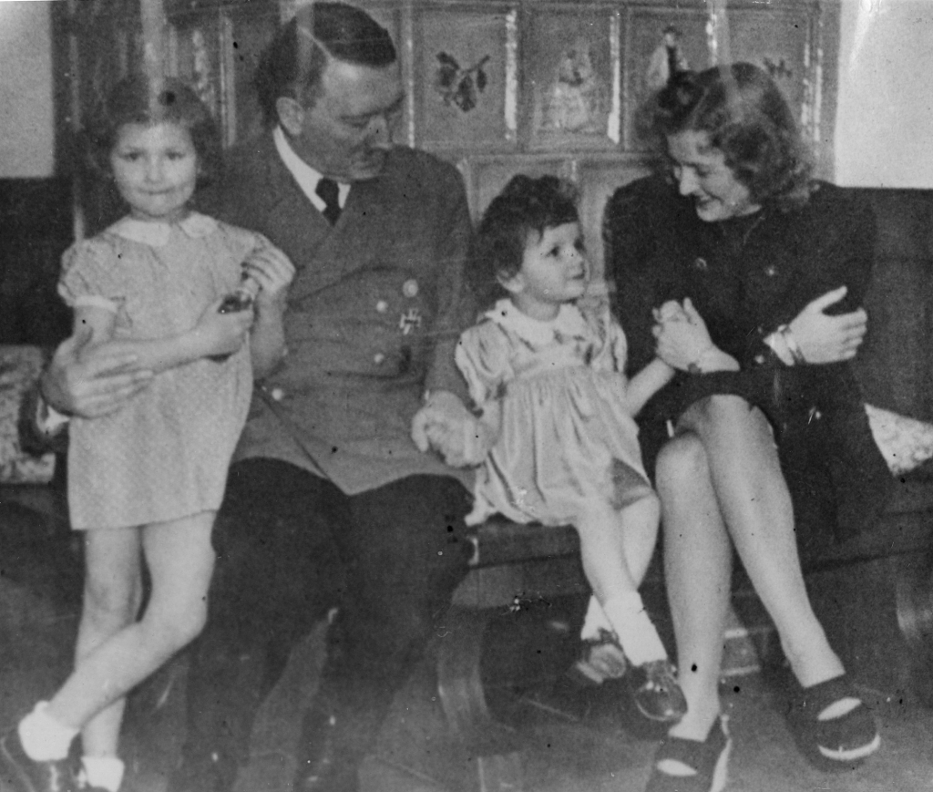 Braun relaxing with Hitler, and two unknown children.