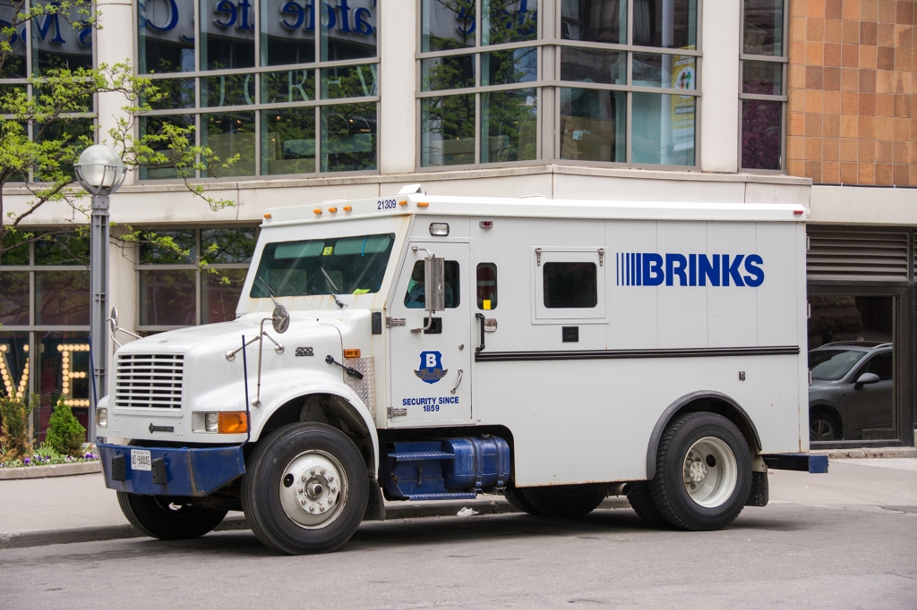 White Brinks armored security truck parked in front of a building.