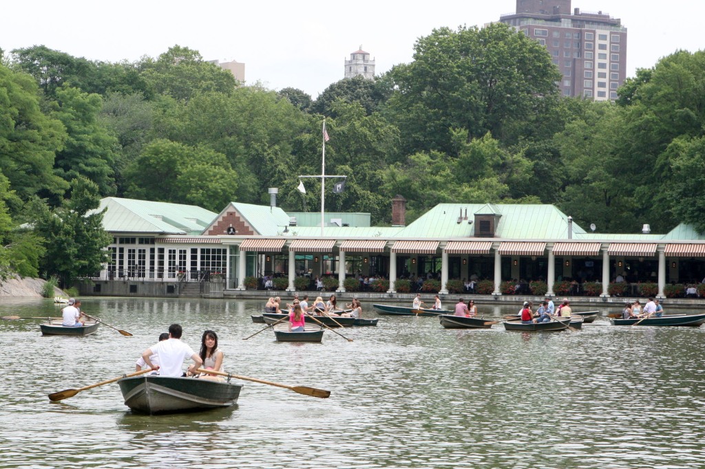 Row boats gliding along the lake at the Loeb Boathouse in Central Park.
